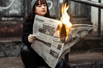 Κοπέλα με εφημερίδα που έχει πάρει φωτιά